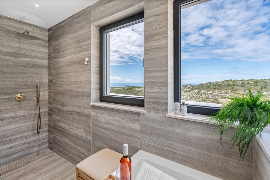 An en-suite bathroom with a bathtub and a shower, a double sink, and a toilet