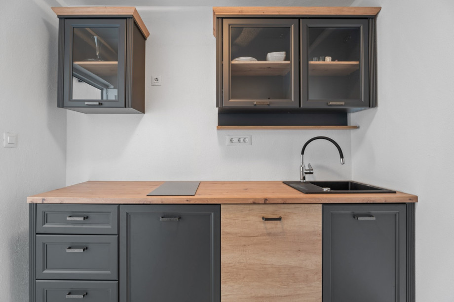 A closed summer kitchen that consists of a fridge, dishwasher, hob, and a separate toilet