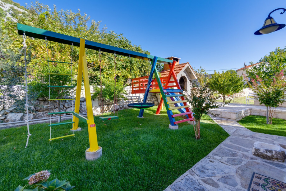 Playground with swing and slide next to barbecue