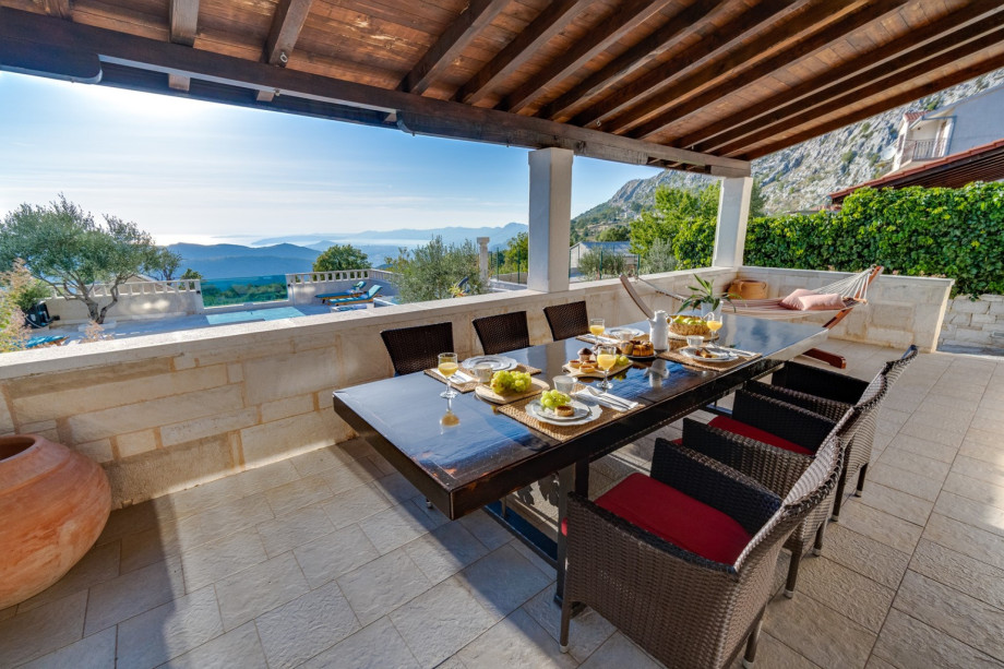 Spacious, covered terrace with outdoor dining area between pool and living area
