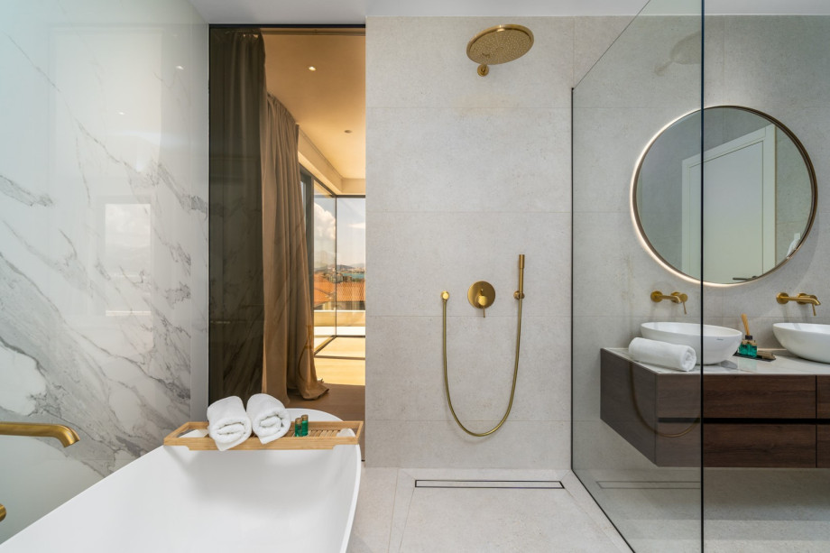 An en-suite bathroom with a bathtub, a shower, double-sink, and a toilet