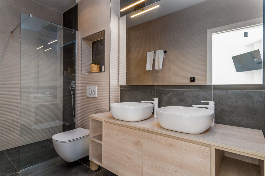 An en-suite bathroom with a shower, a double sink, and a toilet.
