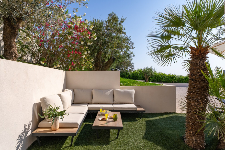 Stylisch outdoor lounge area surrouended by lusch Mediterranean greenery, perfect for relaxing