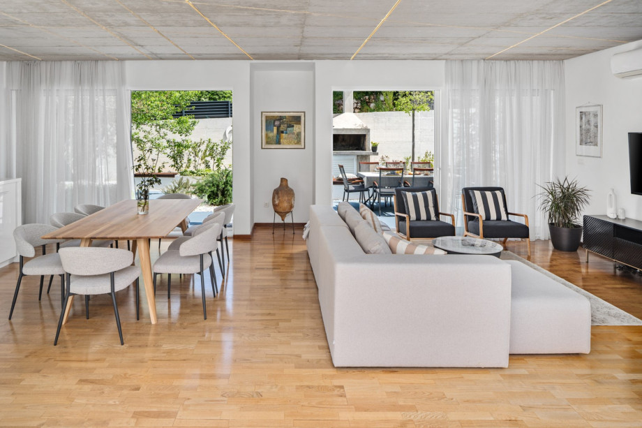 The villa’s design is an open, airy space with large glass doors and windows, flooding the interior with natural light