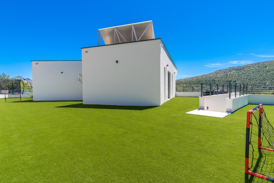 Behind the house, there is an artificial grassplot