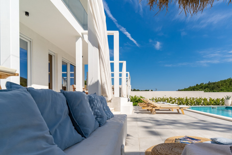 Lounge corner in front of the living room, a summer kitchen with TV, barbecue, dining table for 8, and a toilet