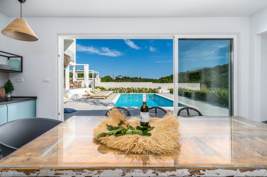 A  summer kitchen with TV, barbecue, dining table for 8, and a toilet