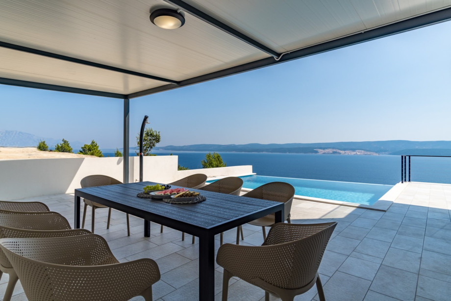 Der Außenbereich bietet einen überdachten Essbereich im Freien mit traditionellem Grill.