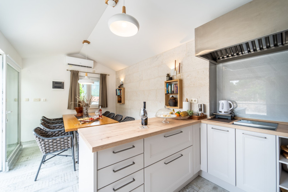 Summer kitchen with a dining table for 10 people with sliding glass doors toward the pool
