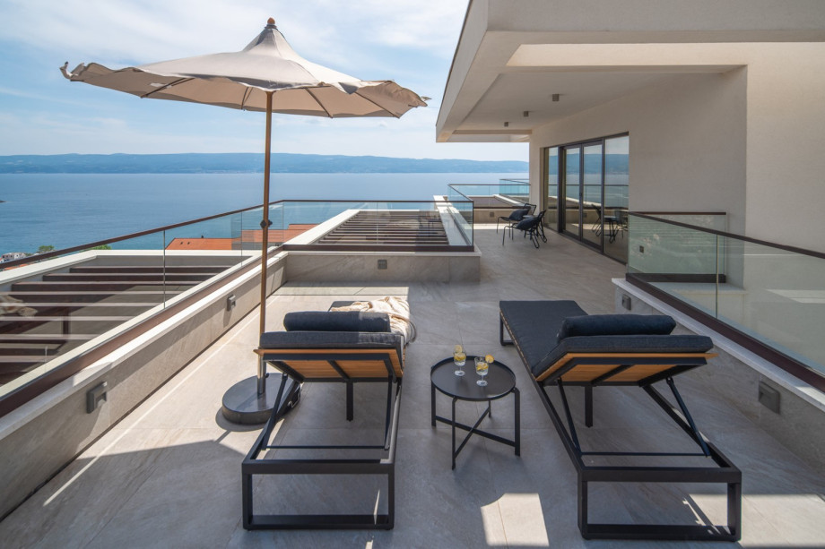 From the hallway, step onto the south terrace with a lounge corner, where spectacular vistas of the sea and nearby islands await.