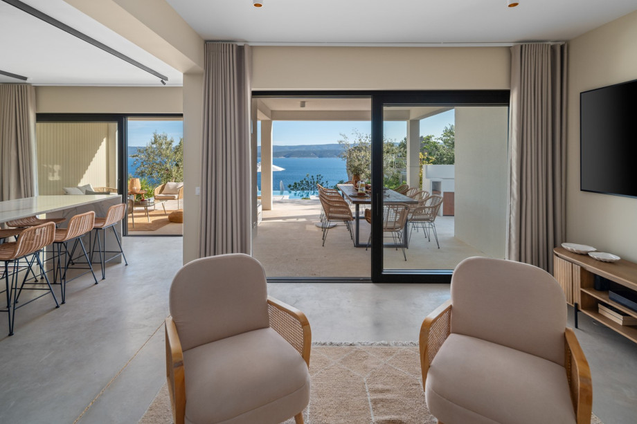 When you step inside, you are greeted by a large lobby that leads to a spacious living room, where floor-to-ceiling windows offer a beautiful view of the Adriatic Sea