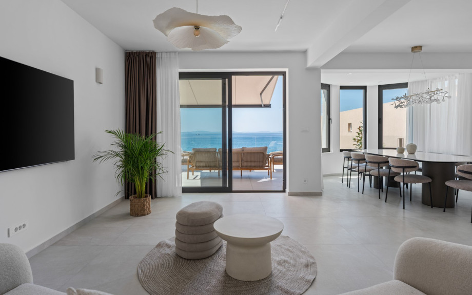 Spacious living room with comfy seating and another TV. The terrace, adorned with a cozy lounge corner, boasts spectacular sea views.