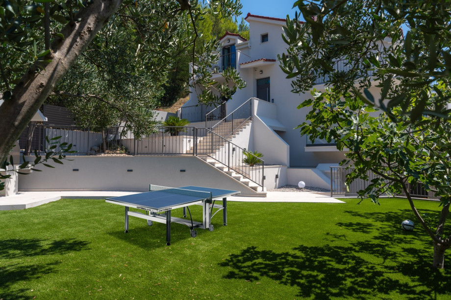 An artificial grass plot equipped with swings, outdoor table tennis, and barbecue facilities, perfect for family activities and gatherings.