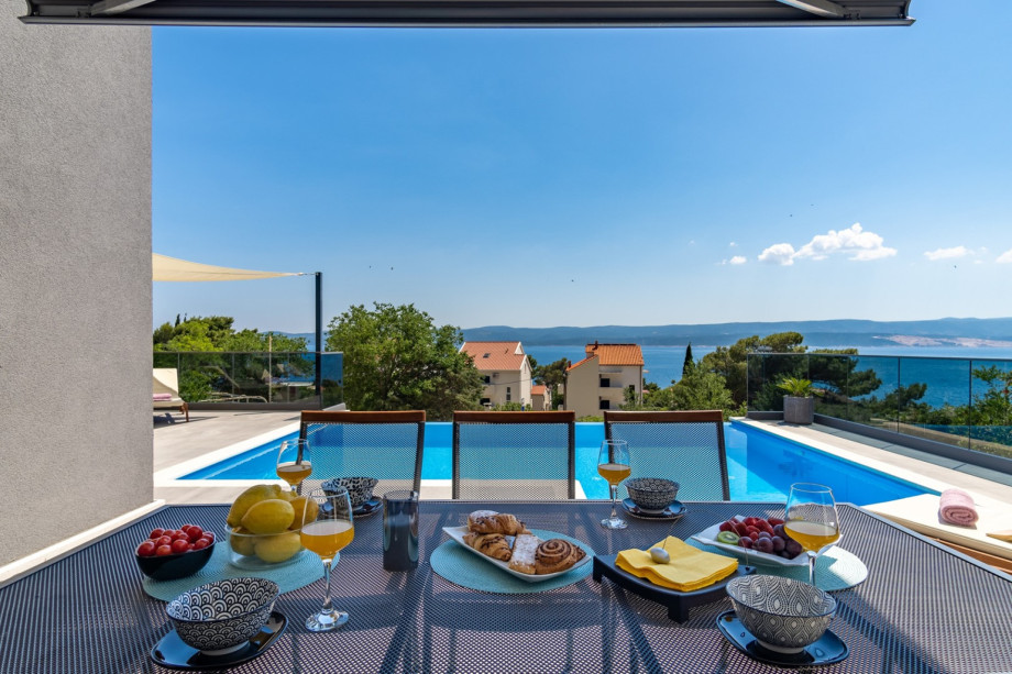 Covered outdoor dining area in front of the kitchen, next to the pool