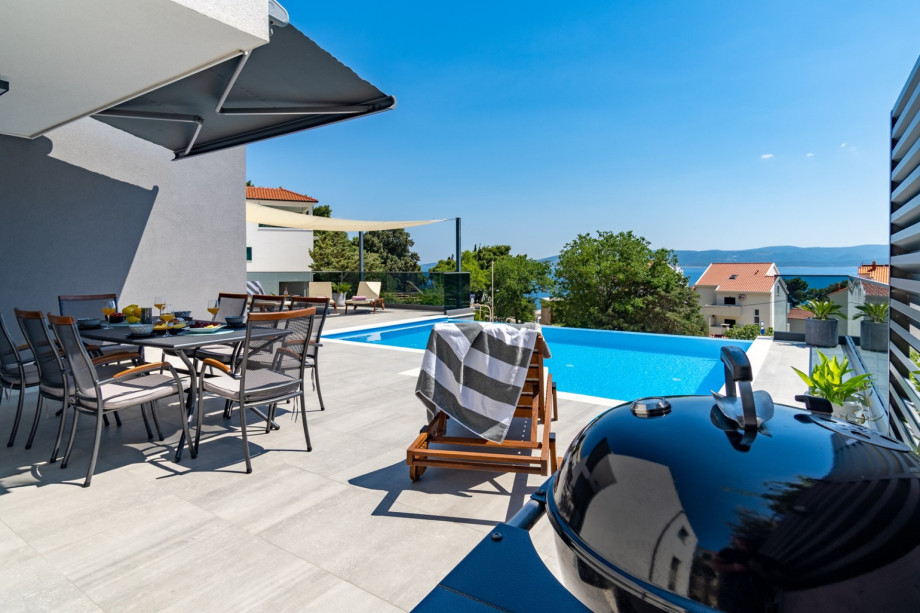 Covered outdoor dining area in front of the kitchen, next to the pool