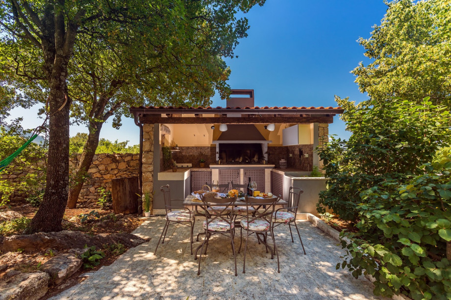 Covered, outdoor kitchen with BBQ and dining area