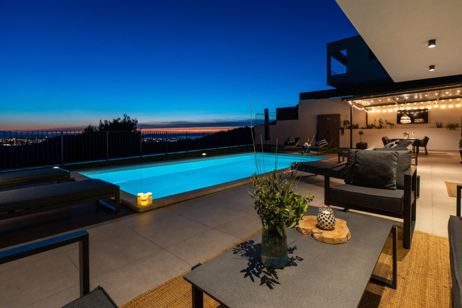 Night view of the lounge corner by the pool and the covered al fresco dining.