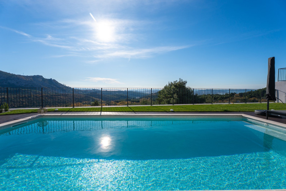 The turquoise 32 sqm pool and green lawn, securely fenced and overlooking the impressive mountains.