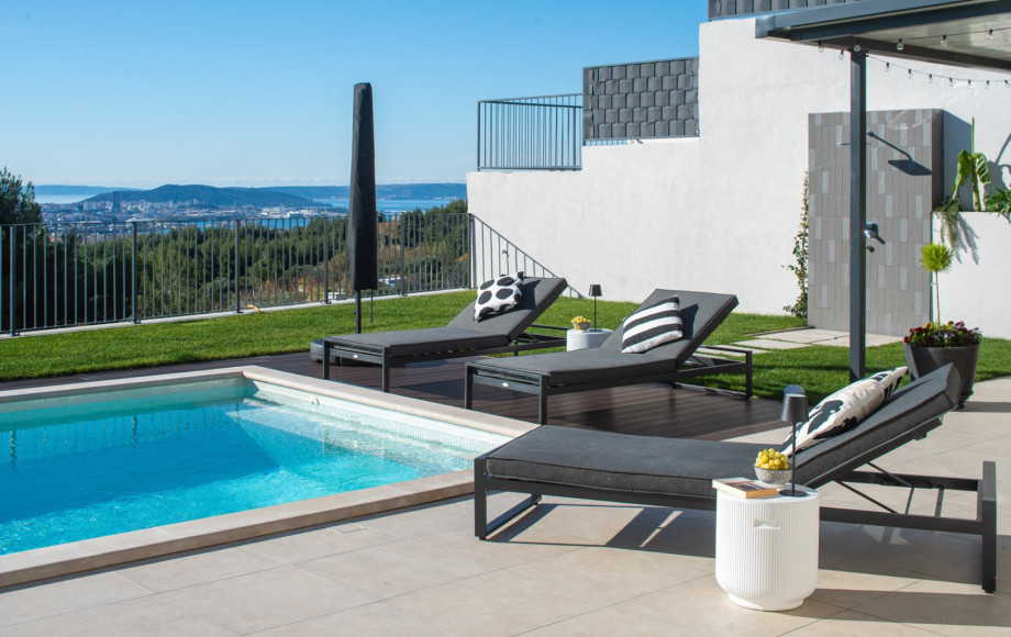 Sun terrace with comfortable loungers overlooking the pool and the distant Split cityscape and islands.