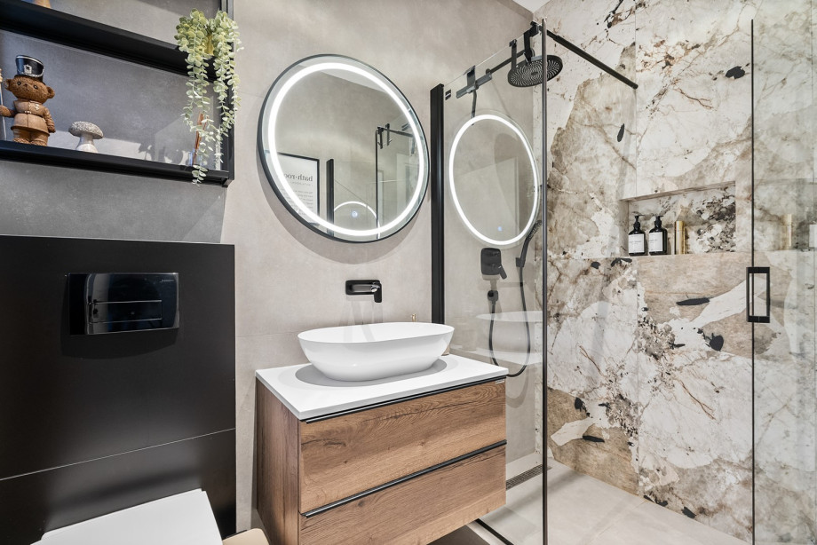 Stylish bathroom with a modern shower, basin, and illuminated mirror for guest convenience.