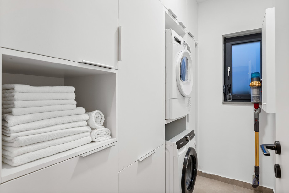 Separate laundry room (3.9 sqm) equipped with a washing machine, dryer, and storage.