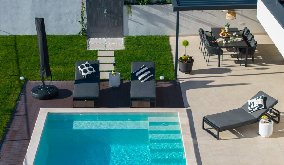 Aerial view of the pool area with the covered al fresco dining space and sun loungers.