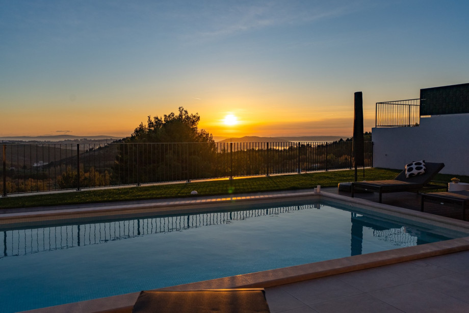 The 32 sqm swimming pool reflects the golden sunset, showcasing the spectacular sea and landscape views.