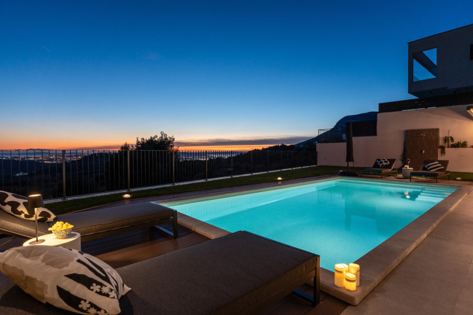 Illuminated private pool and sun loungers at dusk, overlooking the spectacular sea and Split views.