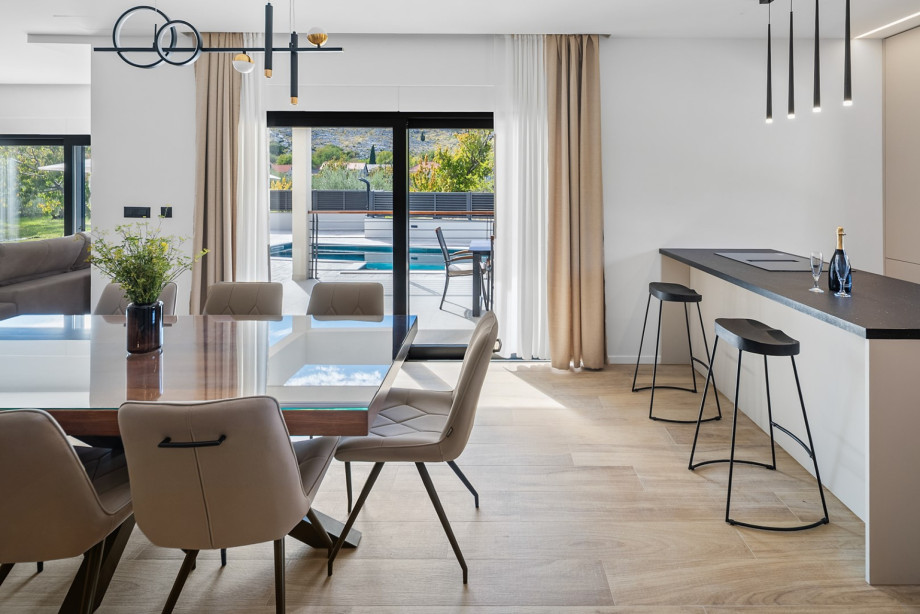 A bright open-plan dining area featuring views of the pool through large, sun-drenched sliding doors.