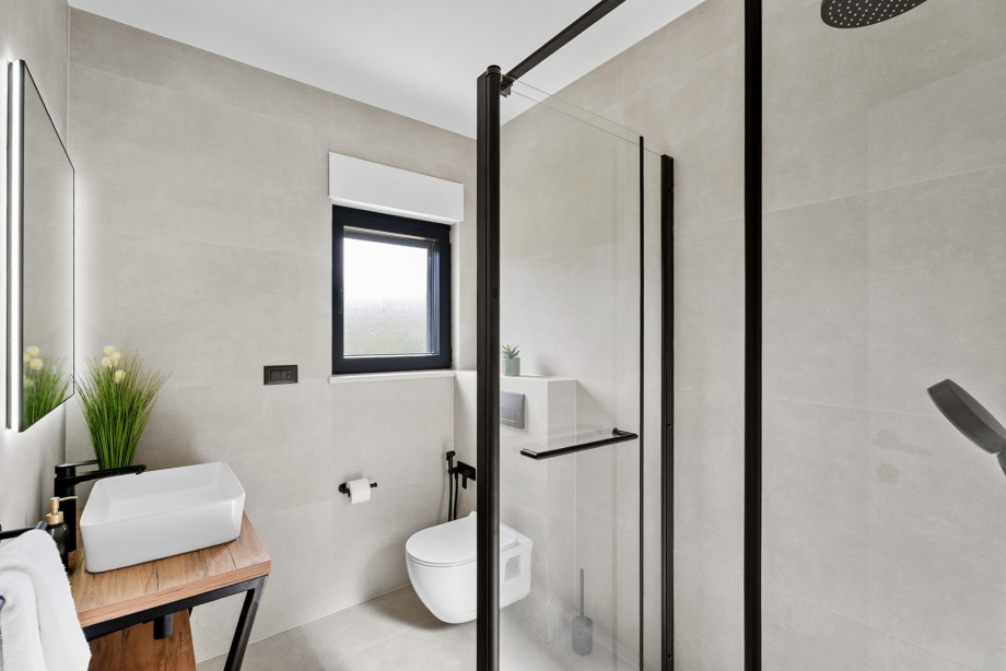 Modern family bathroom with a walk-in shower and minimalist black fixtures.