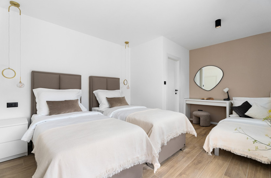 Spacious bedroom accommodating up to three guests, featuring a desk and chic, modern decor.