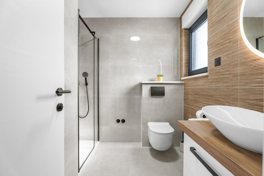 Modern bathroom featuring textured walls, a round mirror, and a clean, bright design.