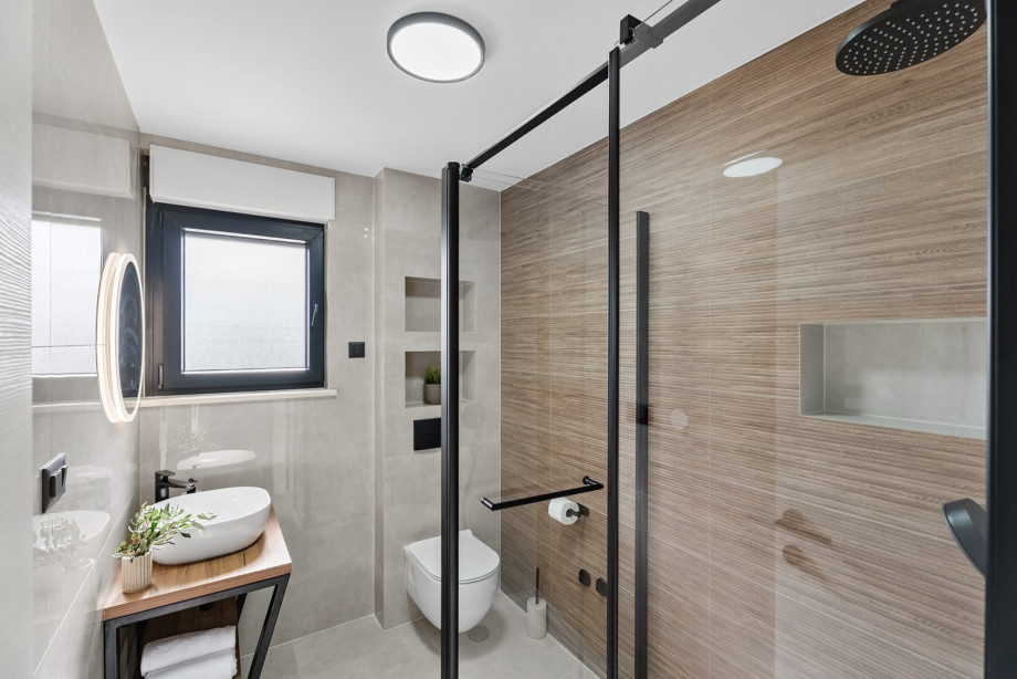 A stylish family bathroom at Villa Agrosa, complete with a modern shower, wood accents, and sleek tiling.