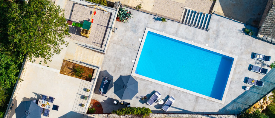 This aerial view showcases the large private swimming pool and the expansive outdoor area, including the sun deck, lounge, and adjacent playground.