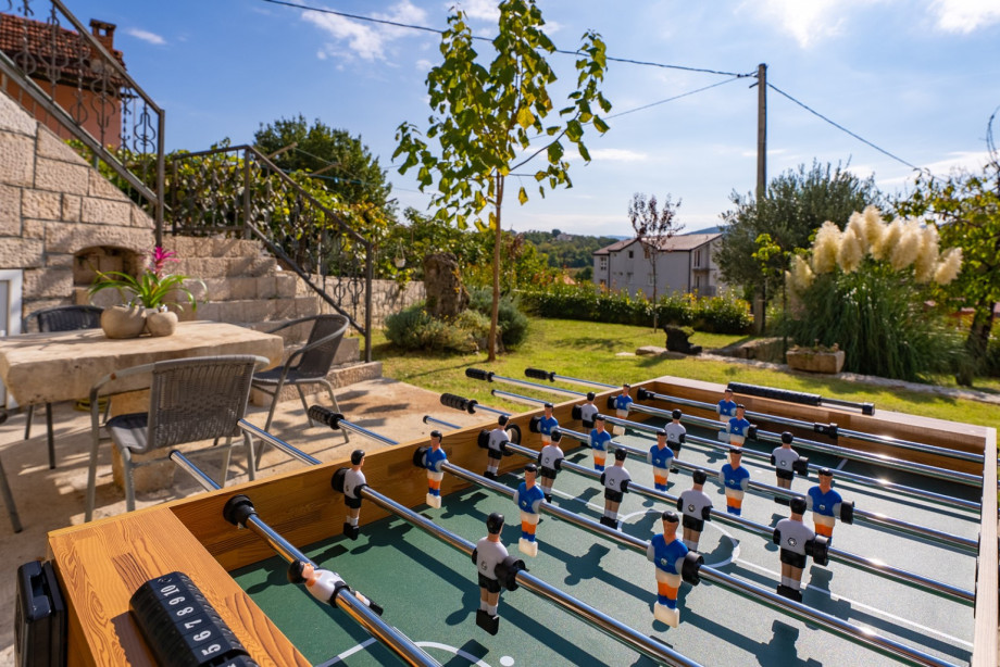 The ground floor's fun zone extends to the outdoors with a table soccer game on a charming stone patio, perfect for entertaining.