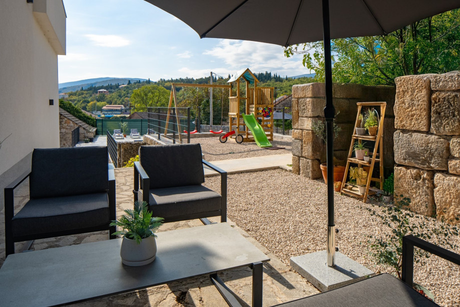 A cosy lounge corner is accessible from the kitchen, offering a shaded retreat near the kids' playground.