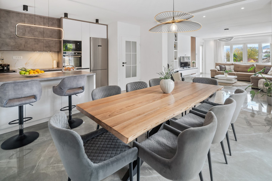 The first floor features a fully equipped kitchen with a kitchen island and a long dining table perfect for family meals, flowing into the spacious living room.
