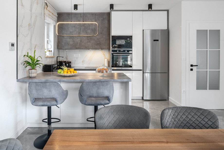 The sleek, fully equipped kitchen on the first floor includes modern appliances, a kitchen island, and a refrigerator.