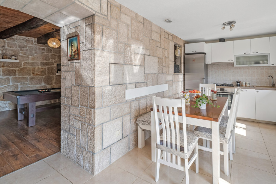 The ground floor contains another fully equipped kitchen with a dining table, set adjacent to the stone-walled fun zone.