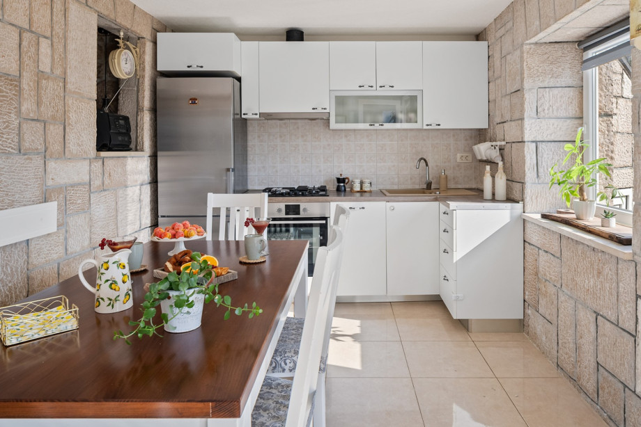 Fully equipped kitchen on the ground floor offers modern appliances and a dining table, maintaining a bright atmosphere.