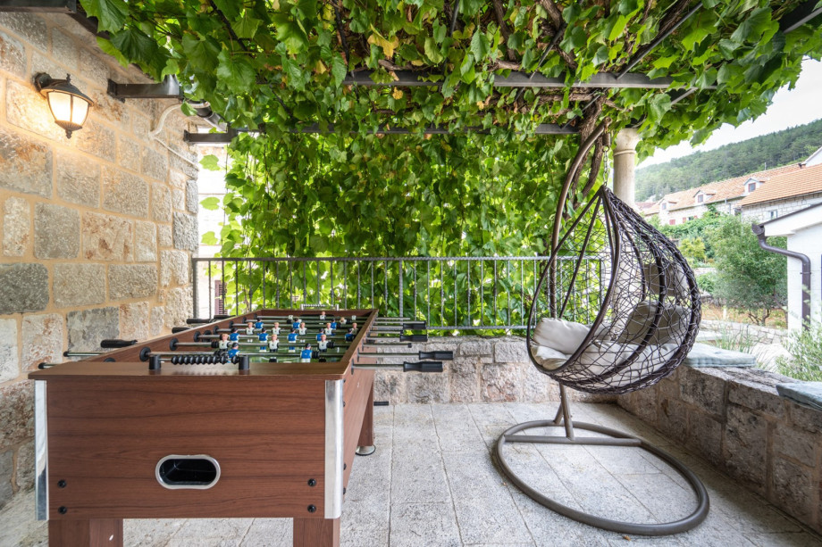 Relaxing outdoor corner with table football and a swing under natural grapevine shade