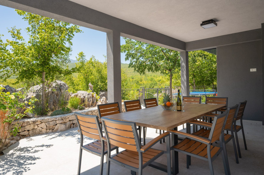 Covered dining patio with a large dining table, ideal for meals with a view of the pool.