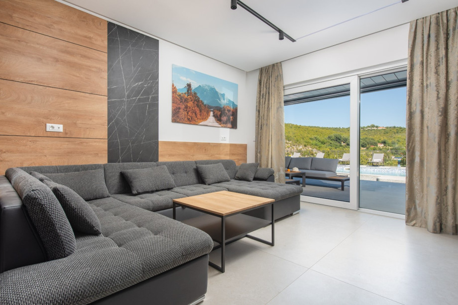 Living area with a comfortable sofa and sliding doors providing beautiful views of the heated pool.