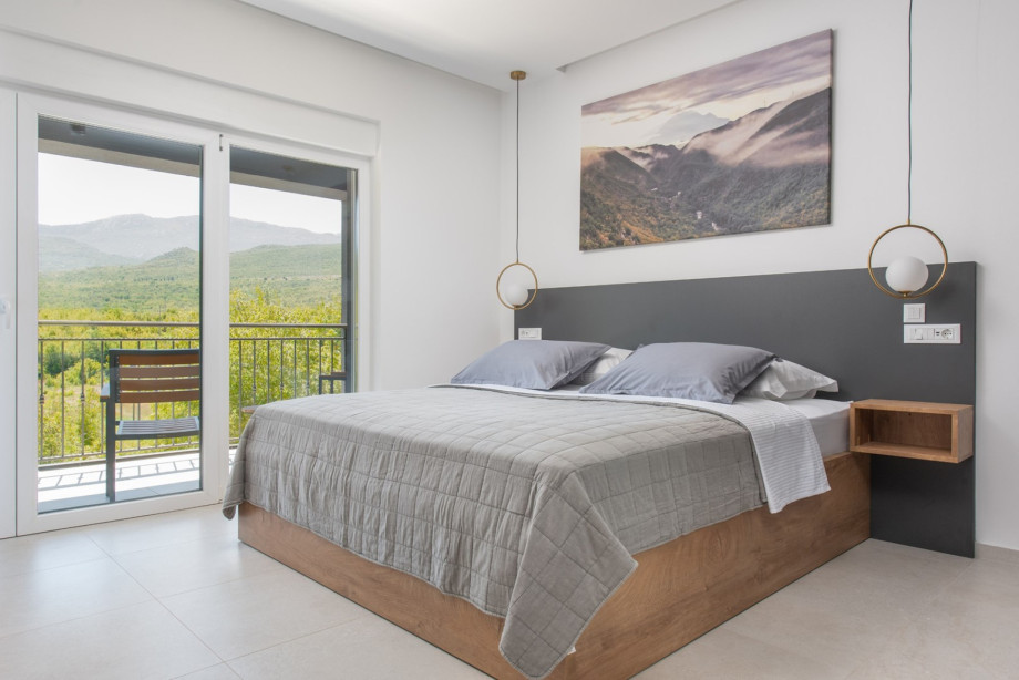 Bedroom with king-size bed, balcony access, smart TV, air conditioning, and serene views.