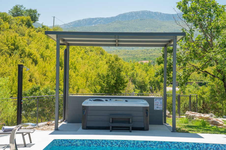 The wellness area includes a covered hot tub and an outdoor shower with mountain views.