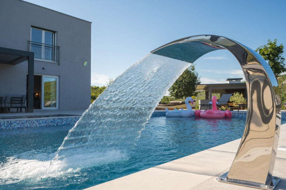 Close-up of the wide waterfall feature flowing into the pool.