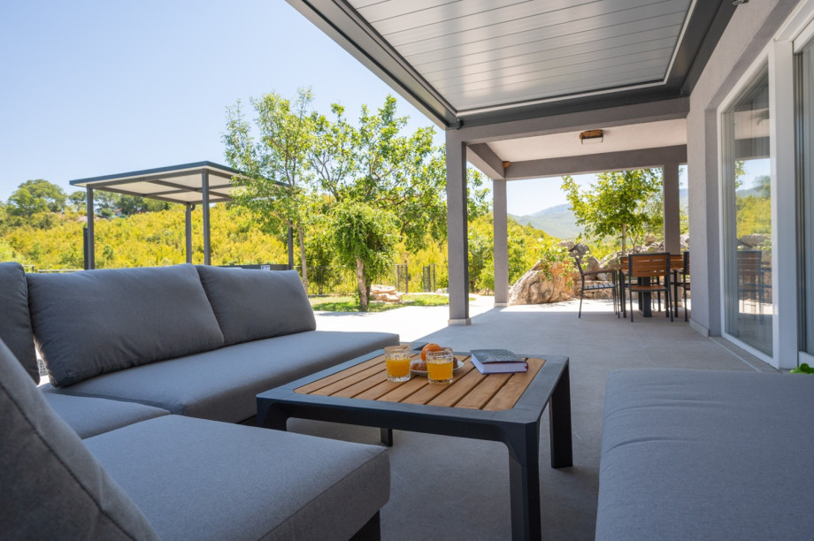 The outdoor terrace includes a dining table and views of nature.