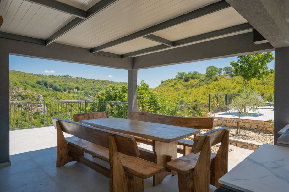 Shaded terrace with a dining table offering views of the valley.