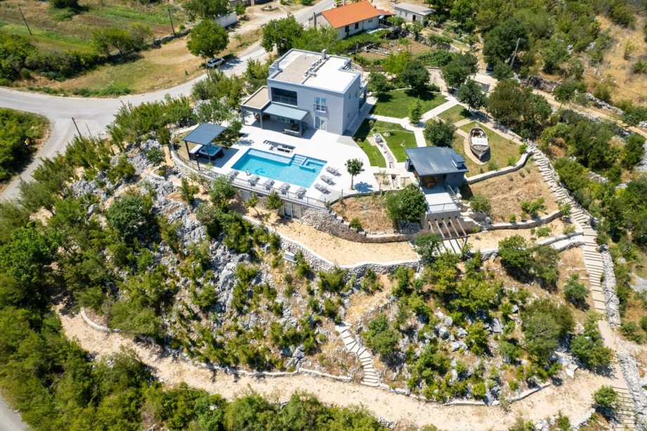The fenced 1,900 sqm private plot includes a heated pool, summer kitchen, and sun deck.