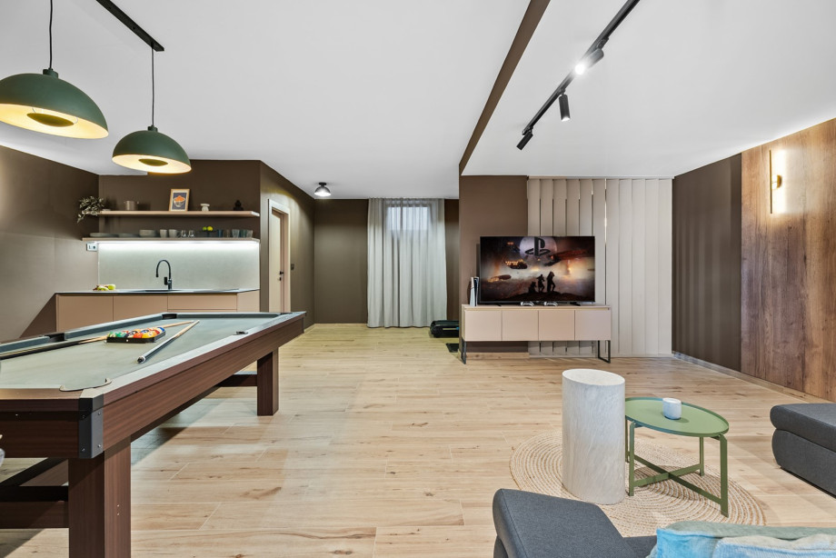 The 55sqm media room features a pool table, PS5, and a comfortable sofa for entertainment.